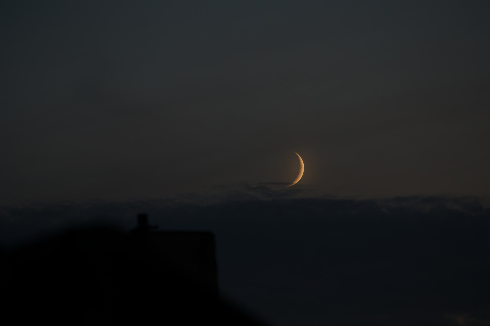 Erste schmale Mondsichel am Horizont