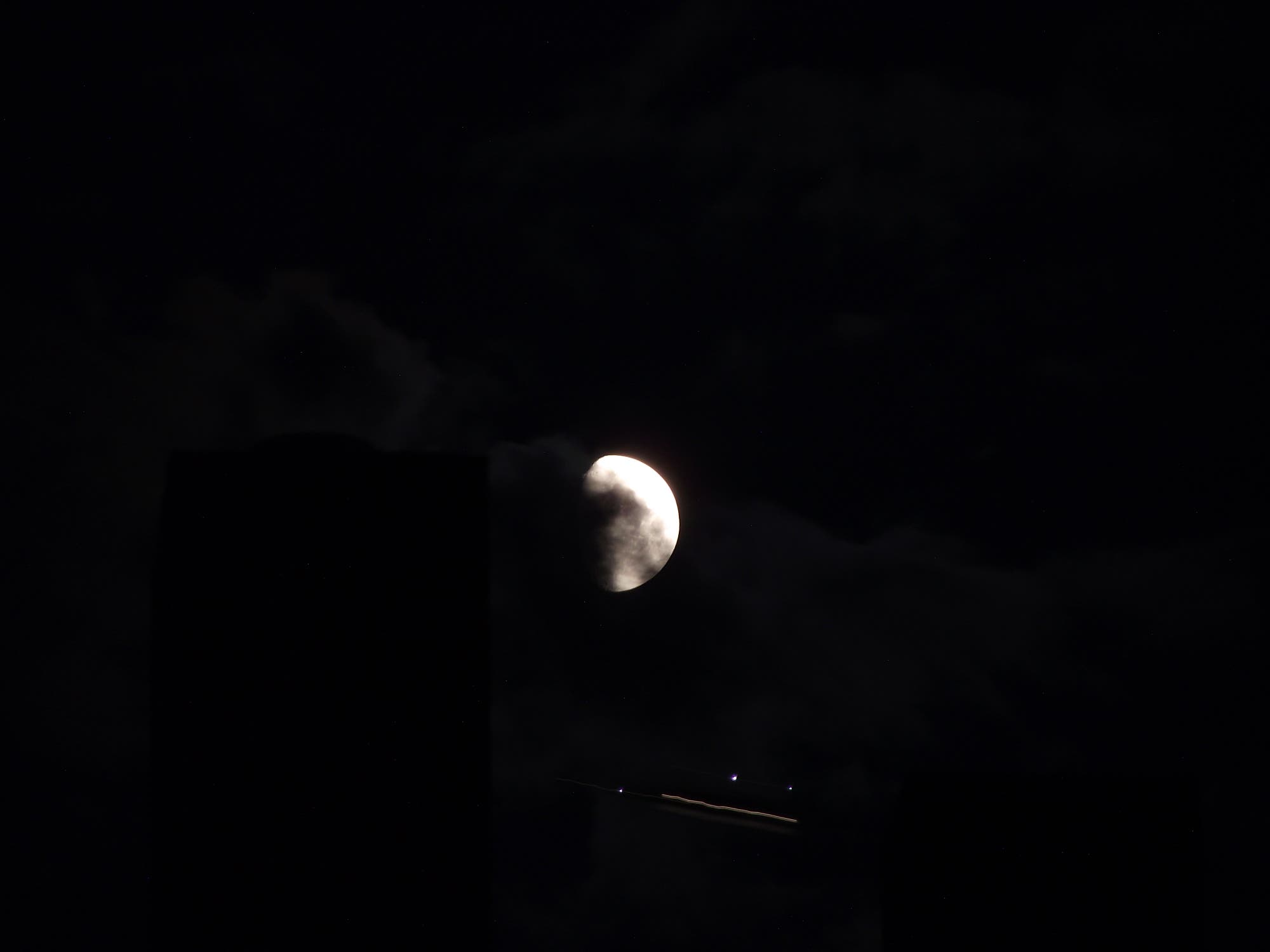 Flugzeuglichter unterhalb des Mondes