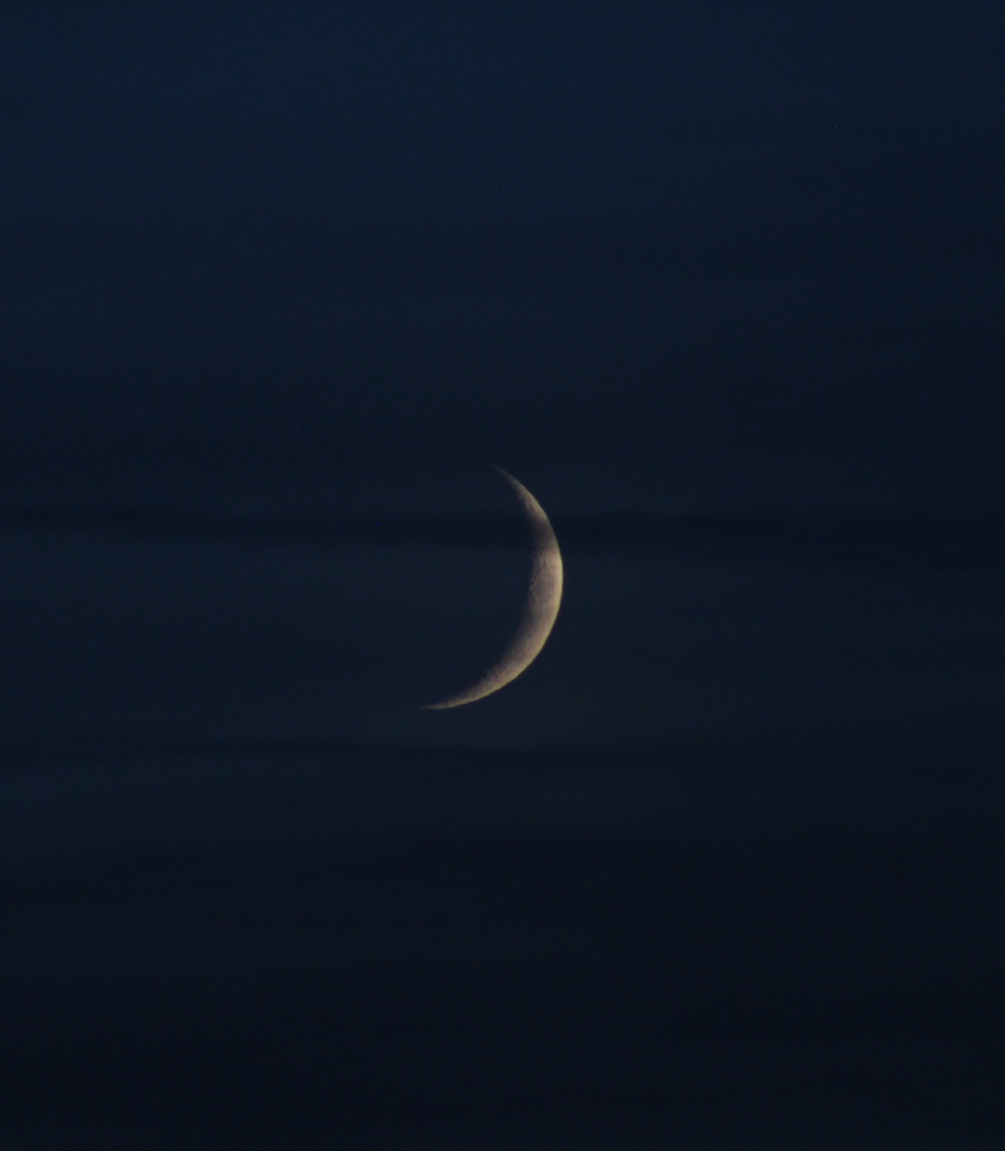 Zunehmende Mondsichel bei bewölktem Himmel