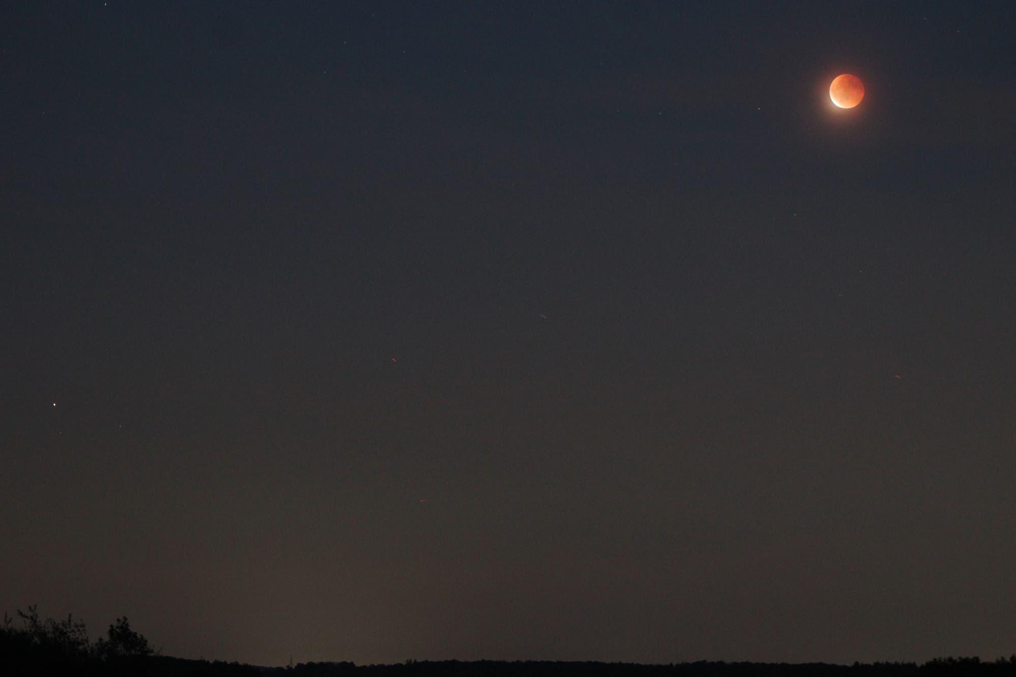 Mond zum Ende der totalen Finsternis mit Hintergrundsternen