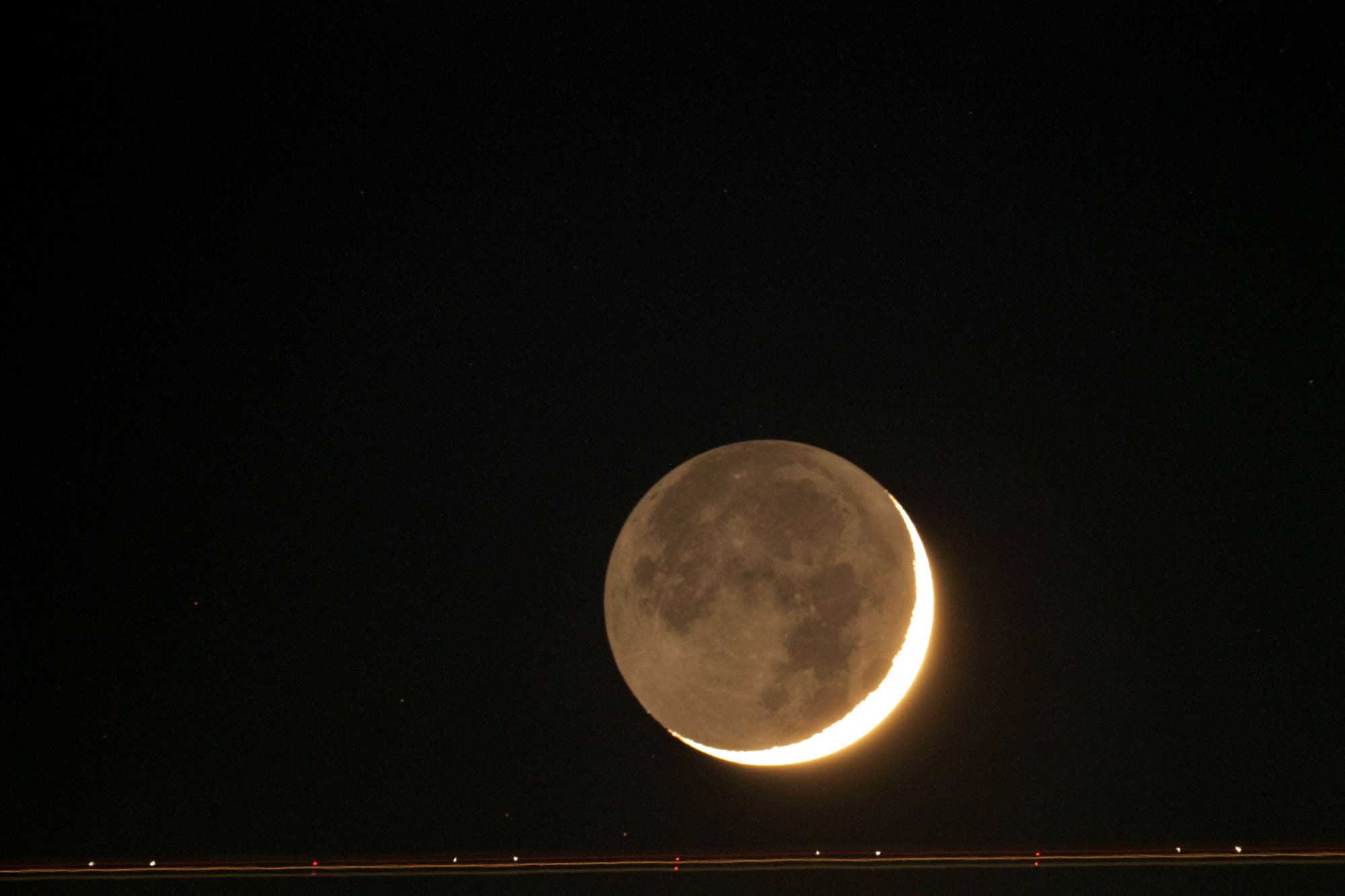 Mond mit sekundärem Mondlicht und Flugzeugspur