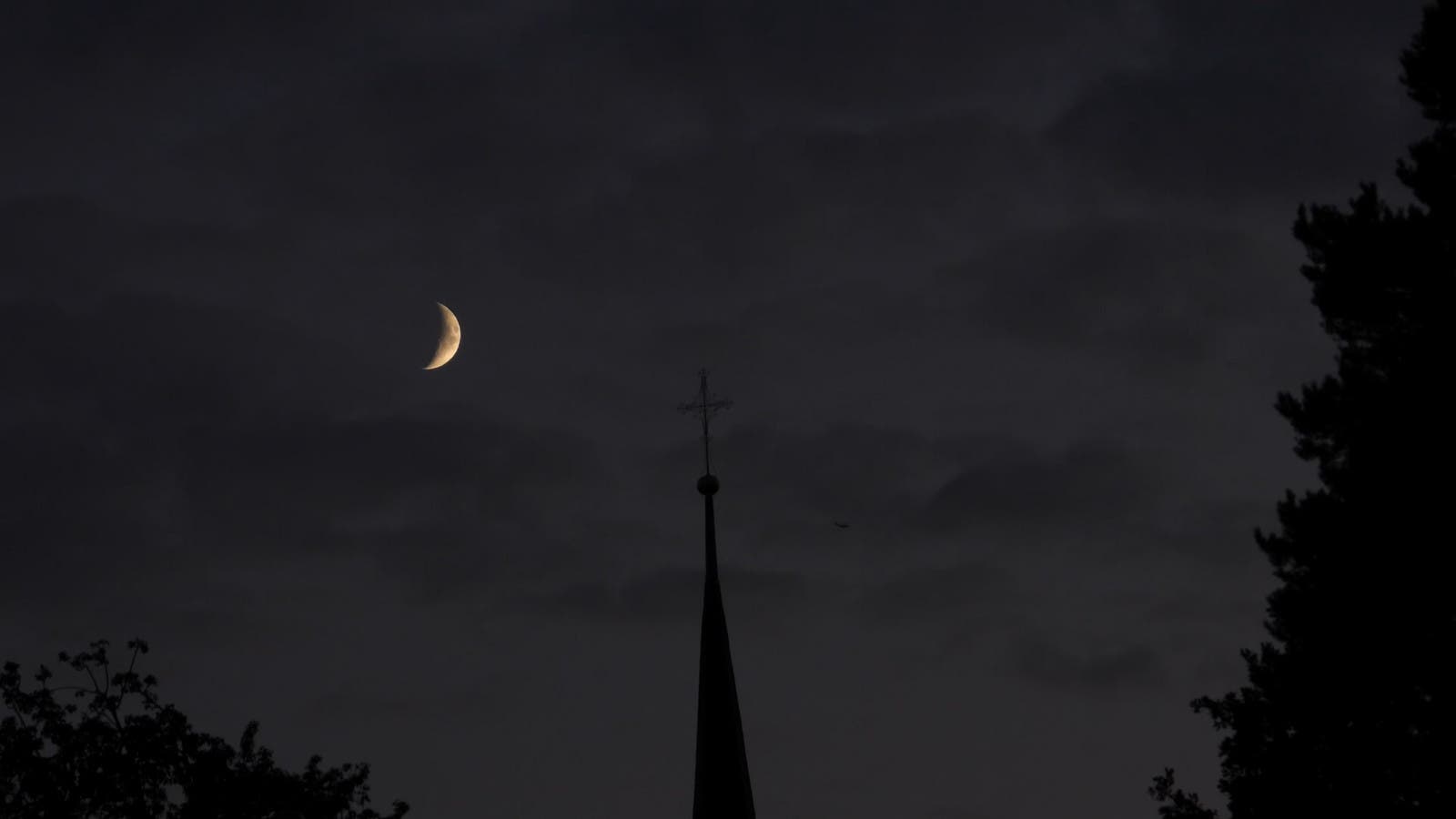 Monduntergang während Sonnenuntergang mit Kirche und Flugzeug