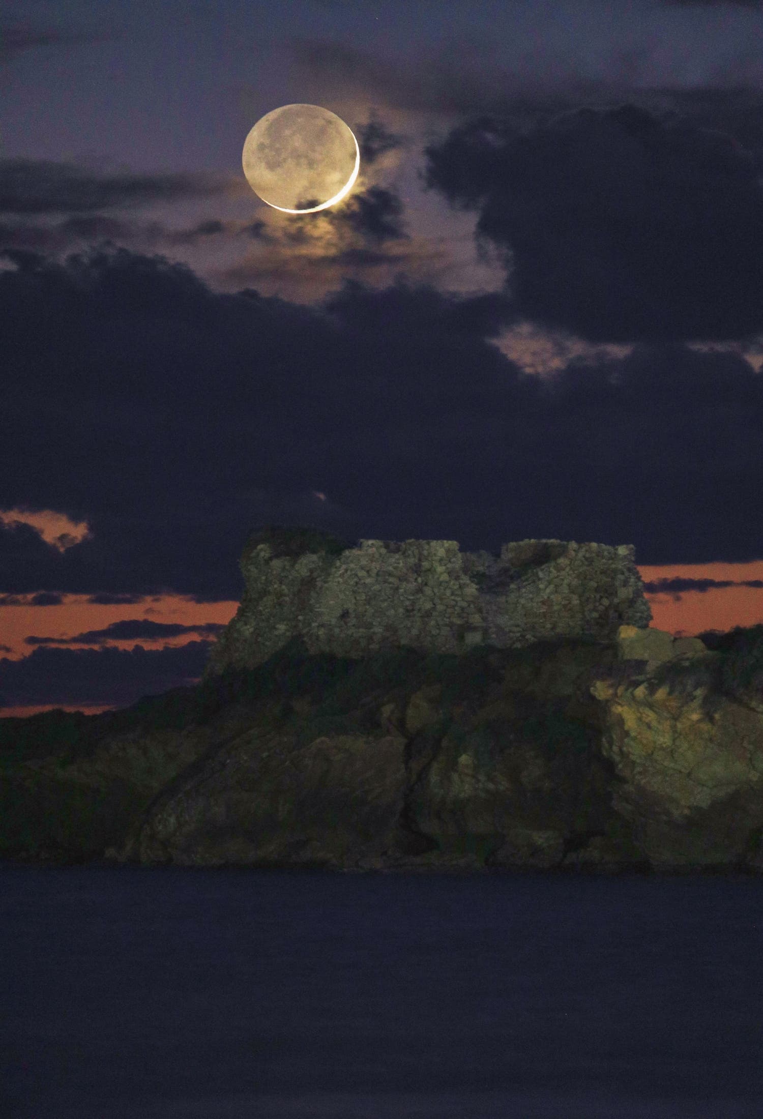 Crescent Moon 1,5 % sets over the ancient Vigliena tower Sicily Punta braccetto