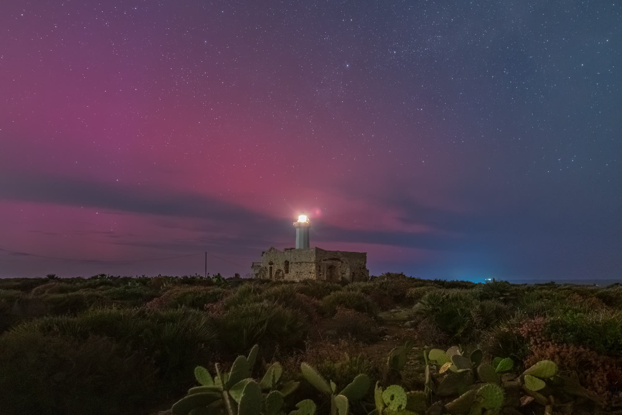 The stable red auroral arc (SAR) colors the sky above the Lighthouse