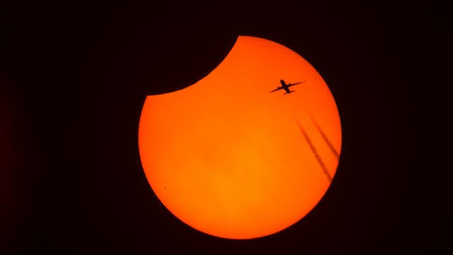 Flugzeug vor der partiell verfinsterten Sonne am 25. Oktober 2022 
