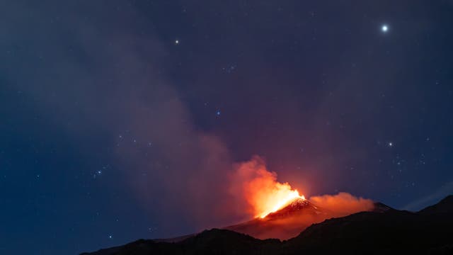 Orion, the hunter, sets over erupting mount Etna