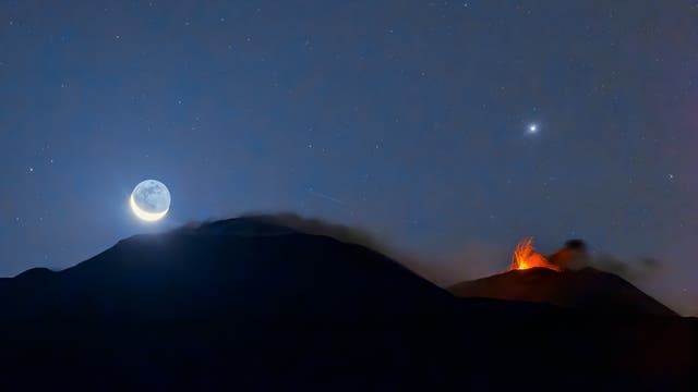 The crescent moon and Jupiter above the erupting Mount Etna