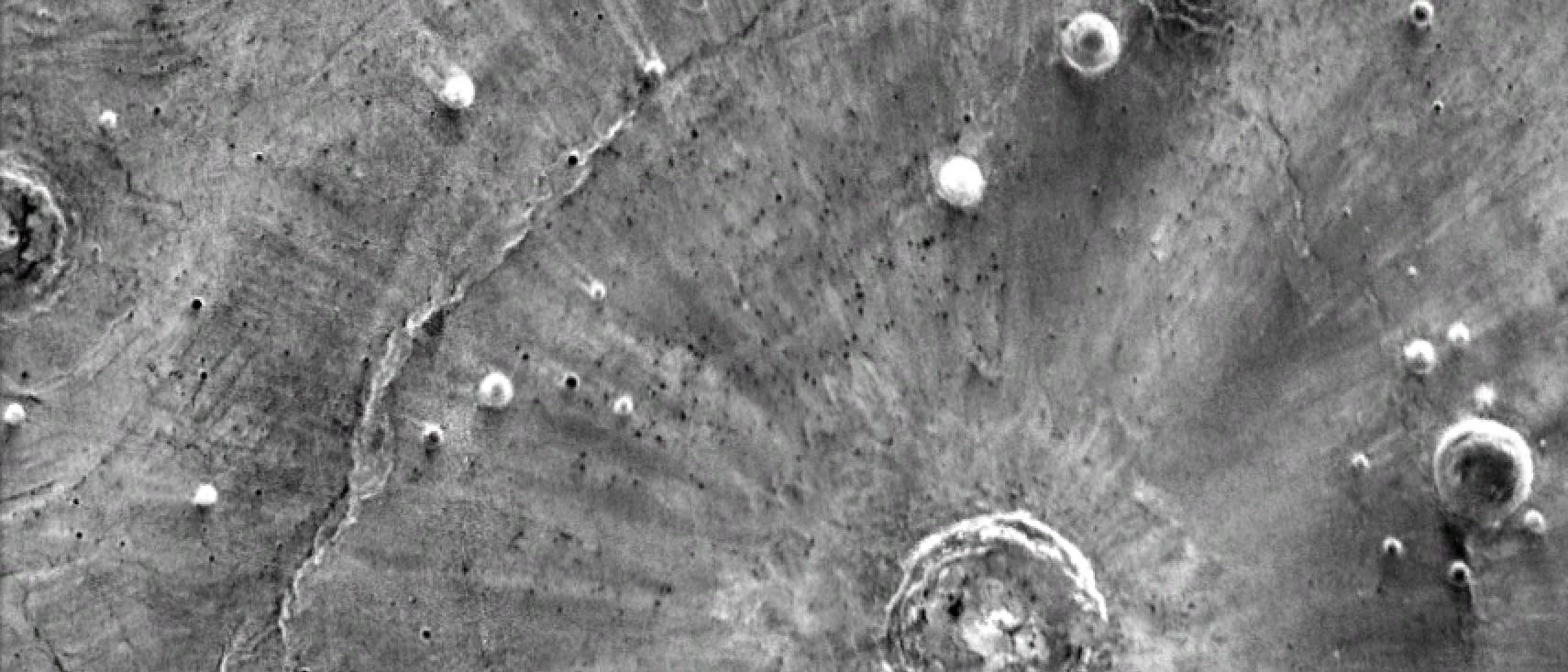 Infrarotaufnahme von der Oberfläche des Mars mit hellen Streifen, die paarweise vom Einschlagort wegzeigen Infrarotaufnahme von der Oberfläche des Mars mit hellen Streifen, die paarweise vom Einschlagort wegzeigen