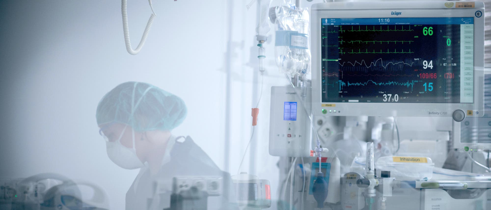 Eine Mitarbeiterin der Pflege in Schutzausrüstung betreut einen Corona-Patienten Eine Mitarbeiterin der Pflege in Schutzausrüstung betreut einen Corona-Patienten
