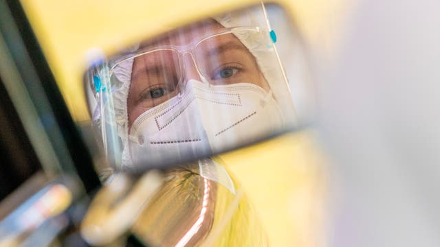 Gurgel-Verfahren to Go: Eine Mitarbeiterin spiegelt sich im Außenspiegel eines Autos, das durch die Teststraße eines Corona-Testzentrums fährt. 
