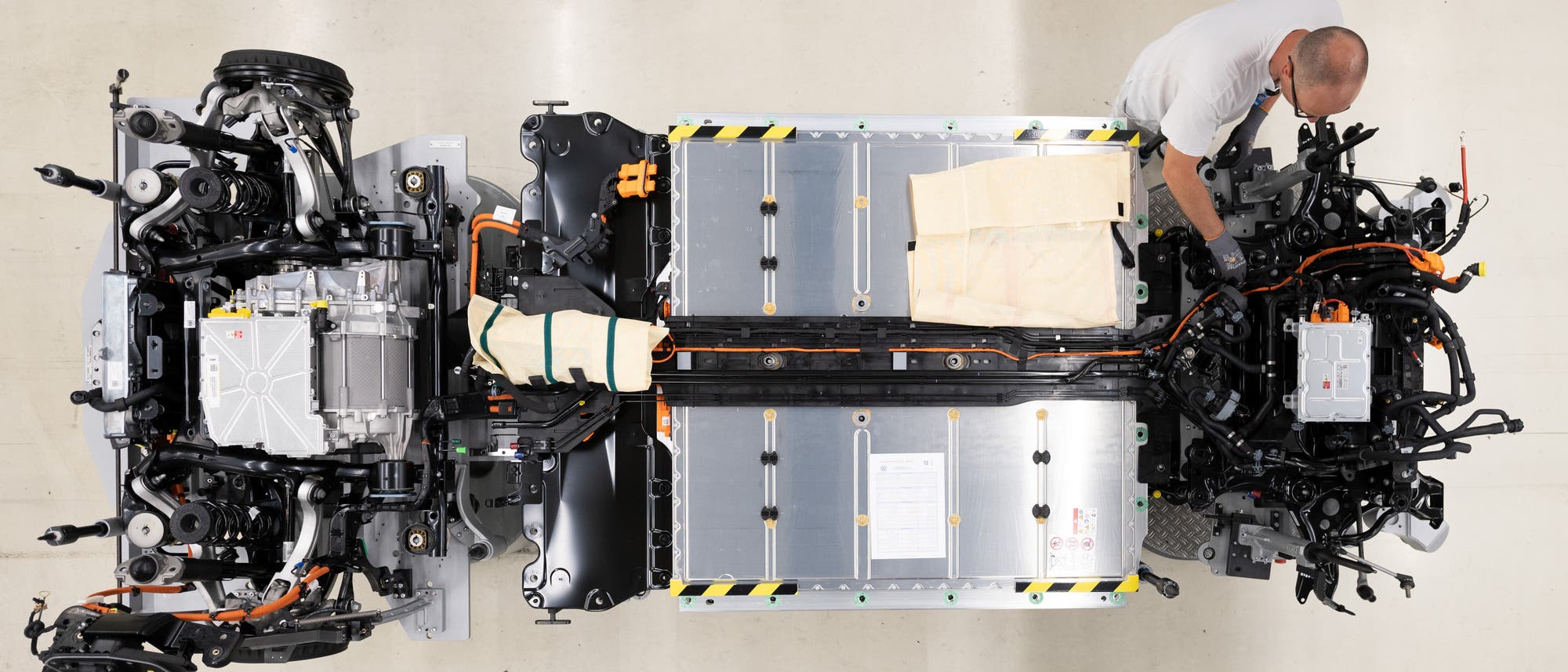 Ein Mitarbeiter von Volkswagen verkabelt den Akku an einem E-Auto. Ein Mitarbeiter von Volkswagen verkabelt den Akku an einem E-Auto.
