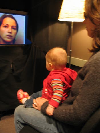 Ein Baby beobachtet die tonlose Sprecherin auf dem Monitor