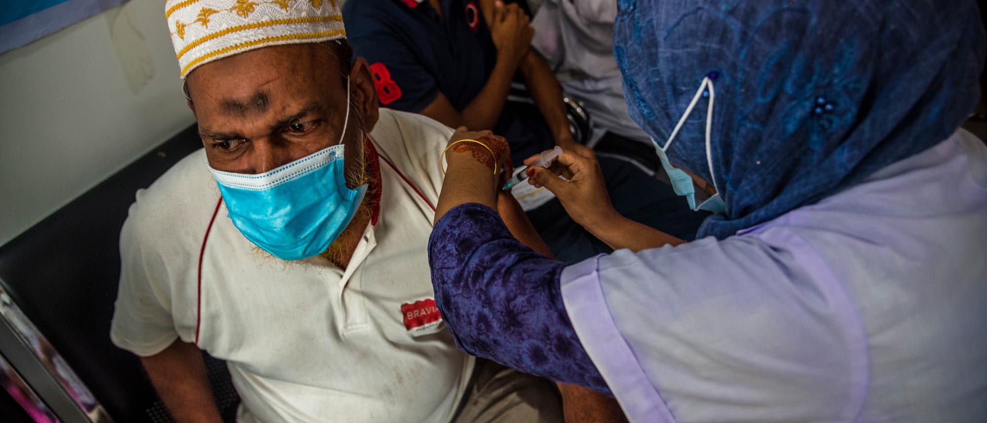 Barishal, Bangladesch: Eine Mitarbeiterin des Gesundheitssystems impft einen Mann während einer Massenimpfung mit Moderna. Barishal, Bangladesch: Eine Mitarbeiterin des Gesundheitssystems impft einen Mann während einer Massenimpfung mit Moderna.