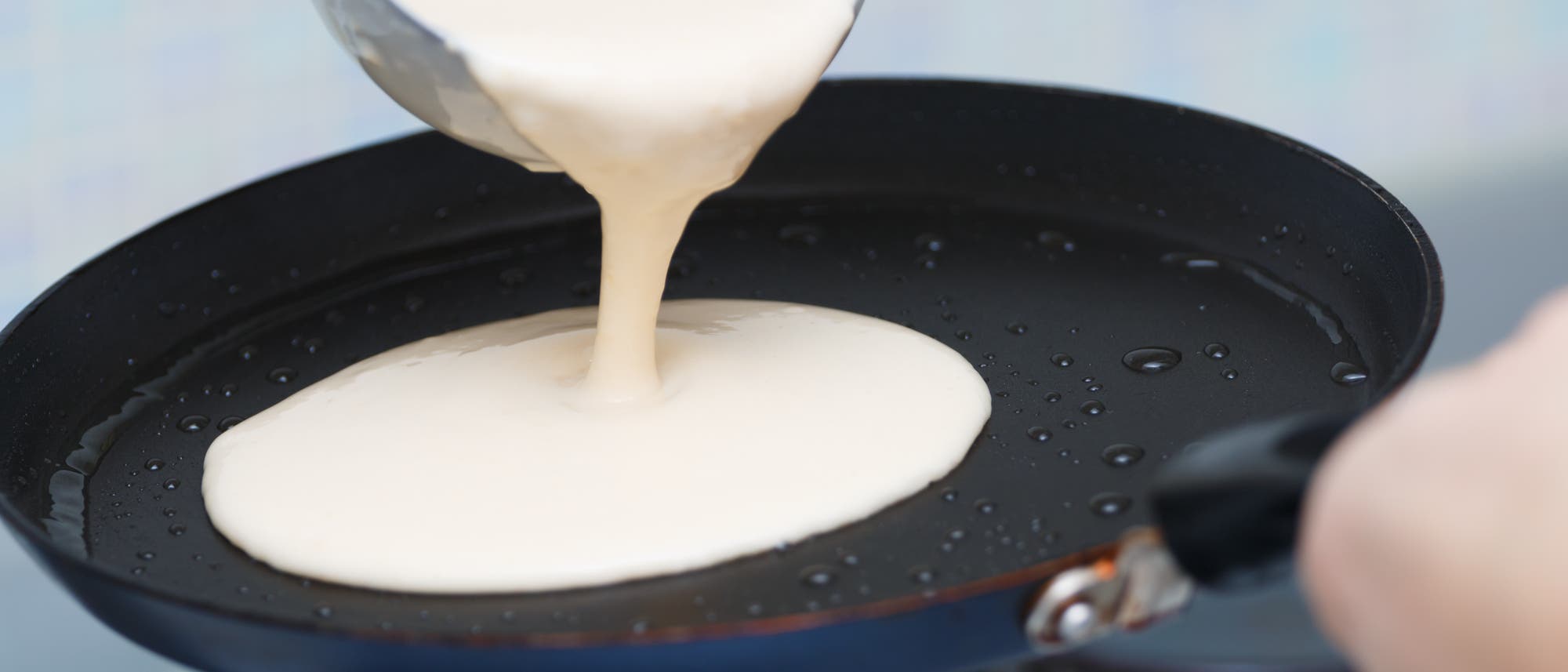 Pfannkuchenteig fließt aus der Kelle in die Pfanne. Ja, die Dinger heißen Pfannkuchen. Pfannkuchenteig fließt aus der Kelle in die Pfanne. Ja, die Dinger heißen Pfannkuchen.