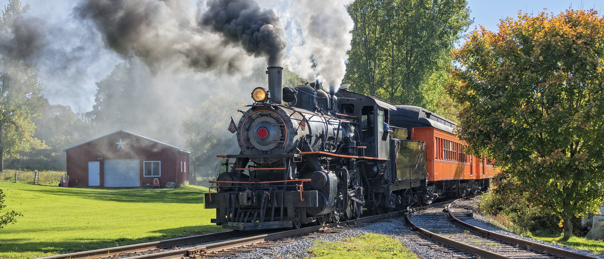 Eine alte Dampflokomotive zieht einen Zug durch den ländlichen Raum.