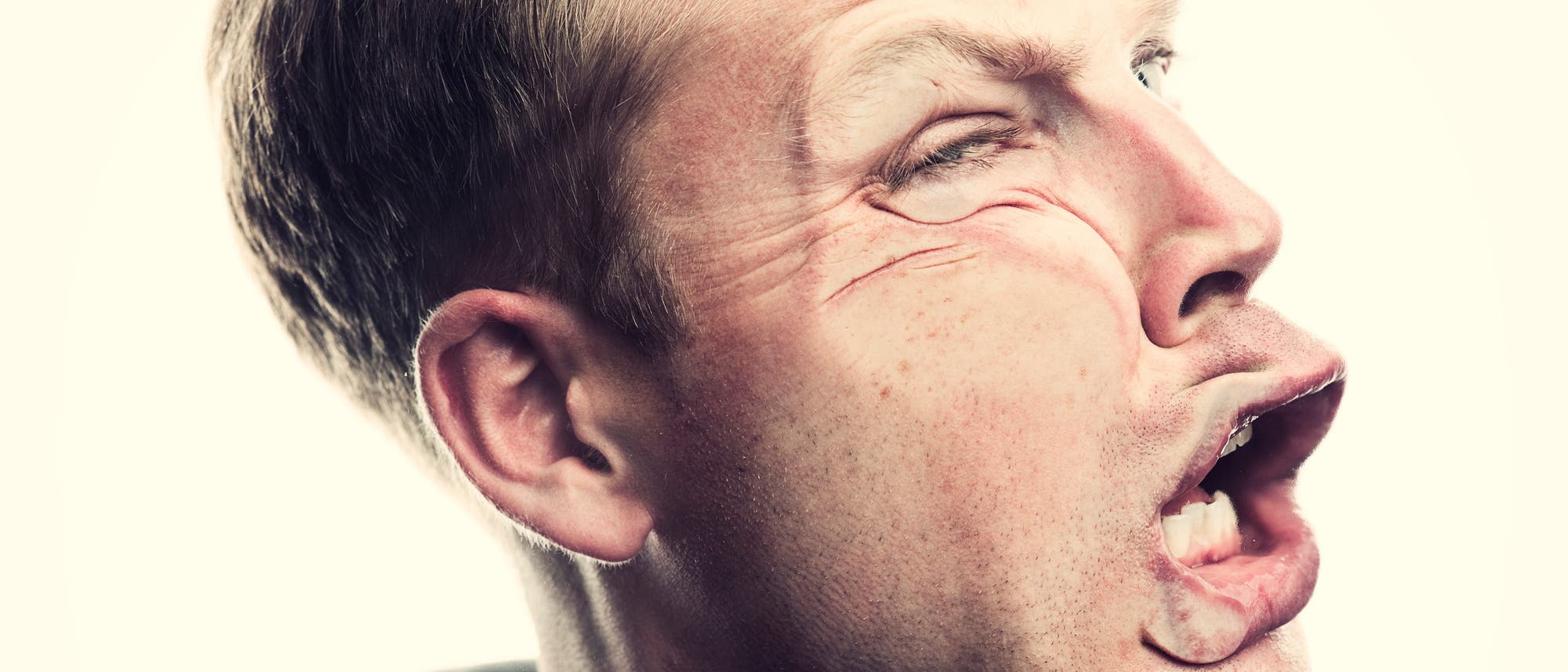 Ein Mann scheint gegen eine unsichtbare Wand zu laufen oder von einem unsichtbaren Objekt im Gesicht getroffen zu werden. Ein Mann scheint gegen eine unsichtbare Wand zu laufen oder von einem unsichtbaren Objekt im Gesicht getroffen zu werden.