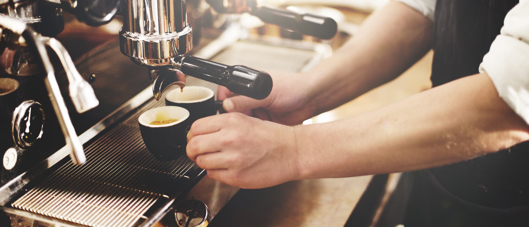 Zwei gefüllte Espressotassen unter der Düse einer Kaffeemaschine. Zwei gefüllte Espressotassen unter der Düse einer Kaffeemaschine.