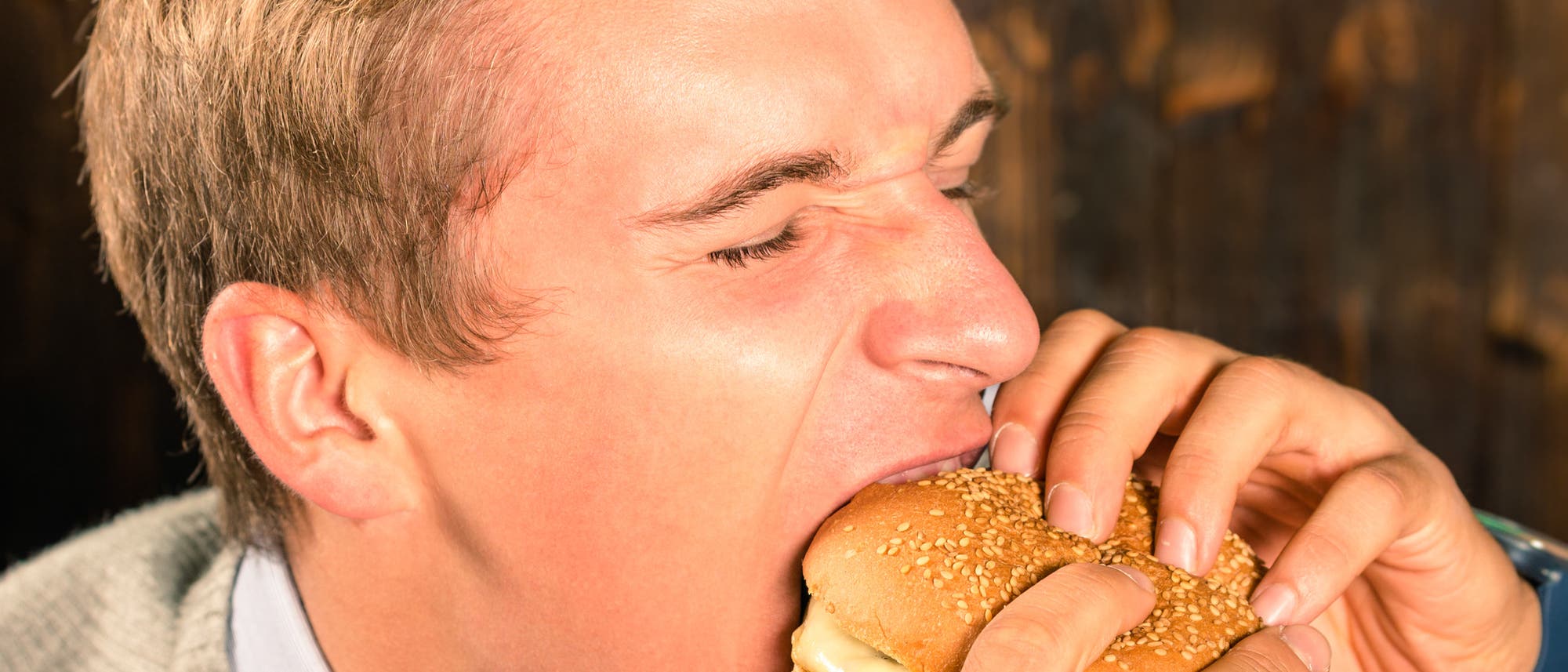 Mann beißt herzhaft in einen Cheeseburger Mann beißt herzhaft in einen Cheeseburger
