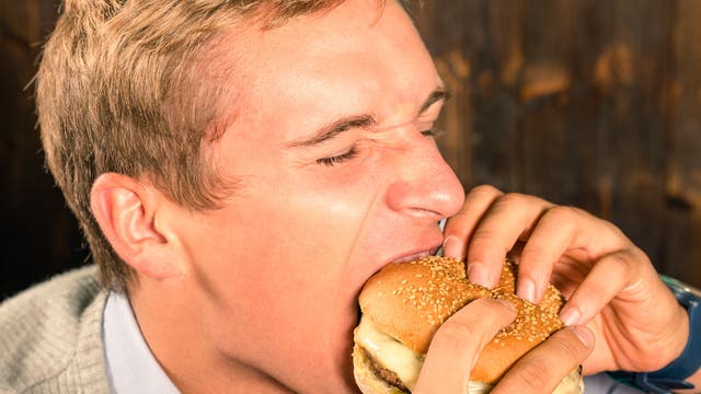 Mann beißt herzhaft in einen Cheeseburger