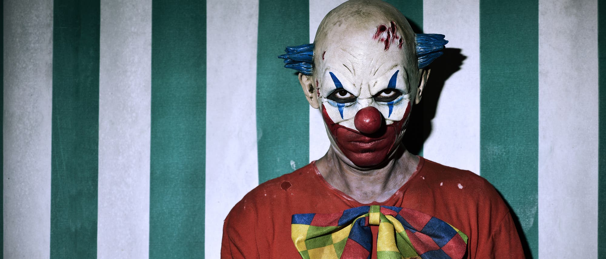 Horror-Clown vor gestreiftem Hintergrund 