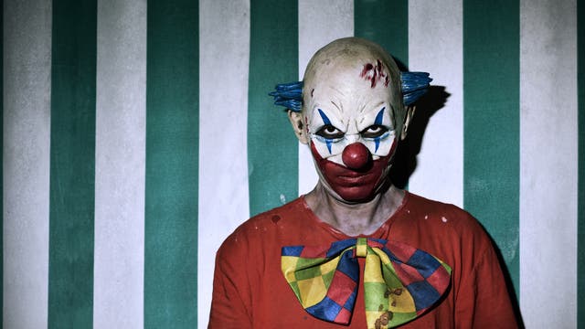 Horror-Clown vor gestreiftem Hintergrund 