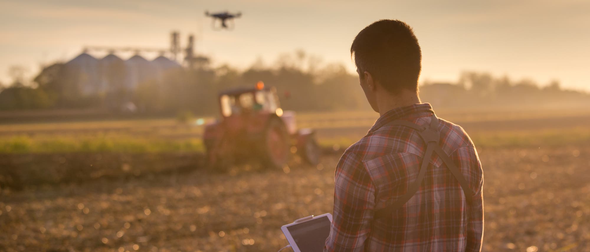 Landwirt überwacht mit Drohne und Tablet die Ernte