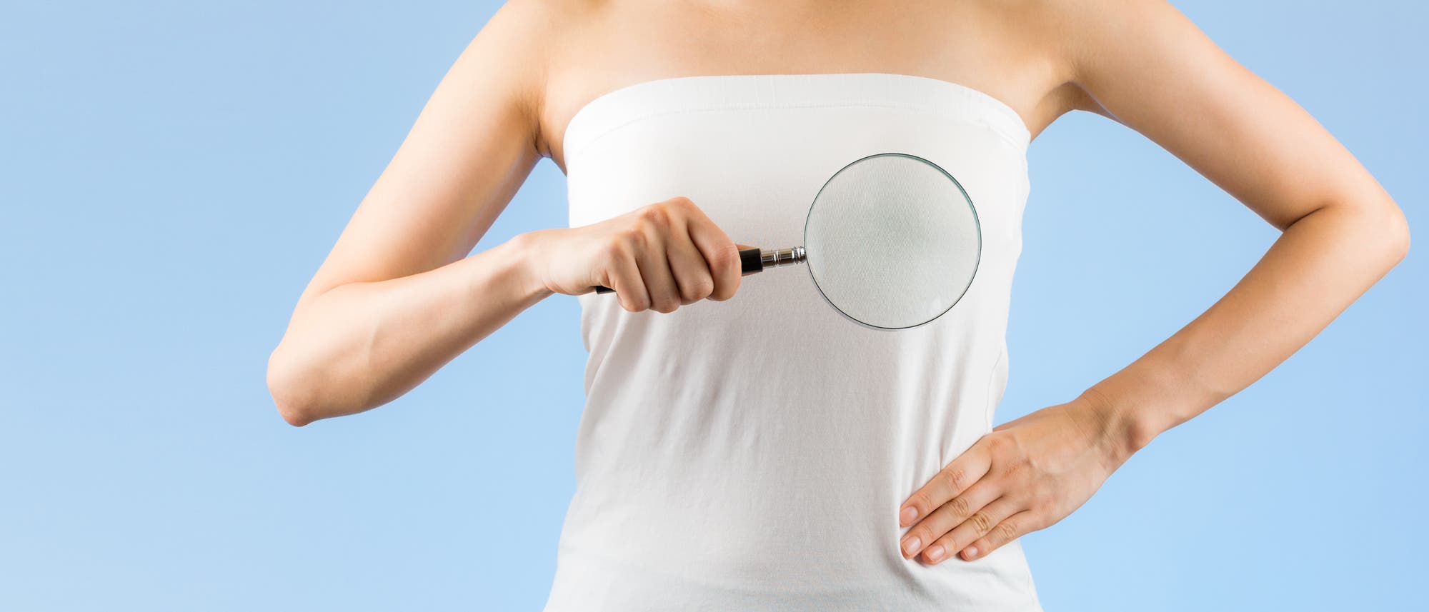 Man sieht den Torso einer Frau, die sich eine altmodische Lupe vor den Körper hält (ein Symbolbild für Brustkrebsvorsorge, kein Fetisch). Man sieht den Torso einer Frau, die sich eine altmodische Lupe vor den Körper hält (ein Symbolbild für Brustkrebsvorsorge, kein Fetisch).