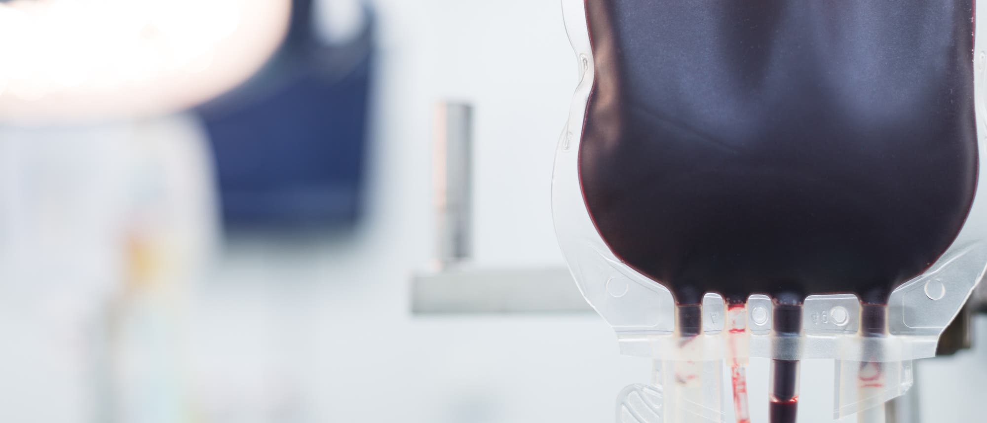 Infusionsbeutel mit Blut hängt vor unscharfem weißem Hintergrund Infusionsbeutel mit Blut hängt vor unscharfem weißem Hintergrund