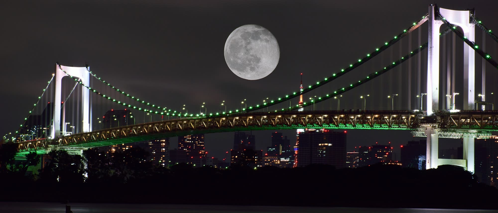 Mond über einer bunt beleuchteten Hängebrücke im Hafen von Tokio Mond über einer bunt beleuchteten Hängebrücke im Hafen von Tokio
