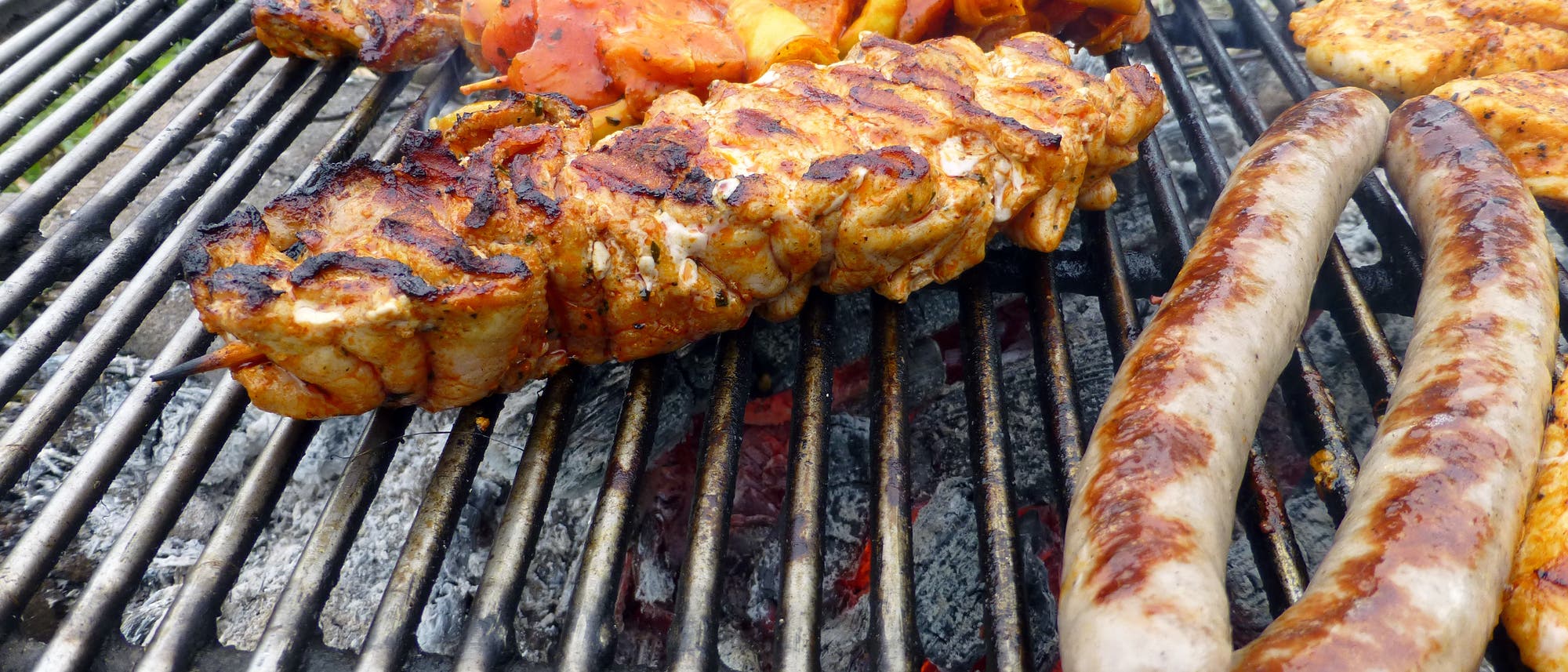 Fleischstücke und Wurst auf einen geringfügig versifften Grillrost Fleischstücke und Wurst auf einen geringfügig versifften Grillrost
