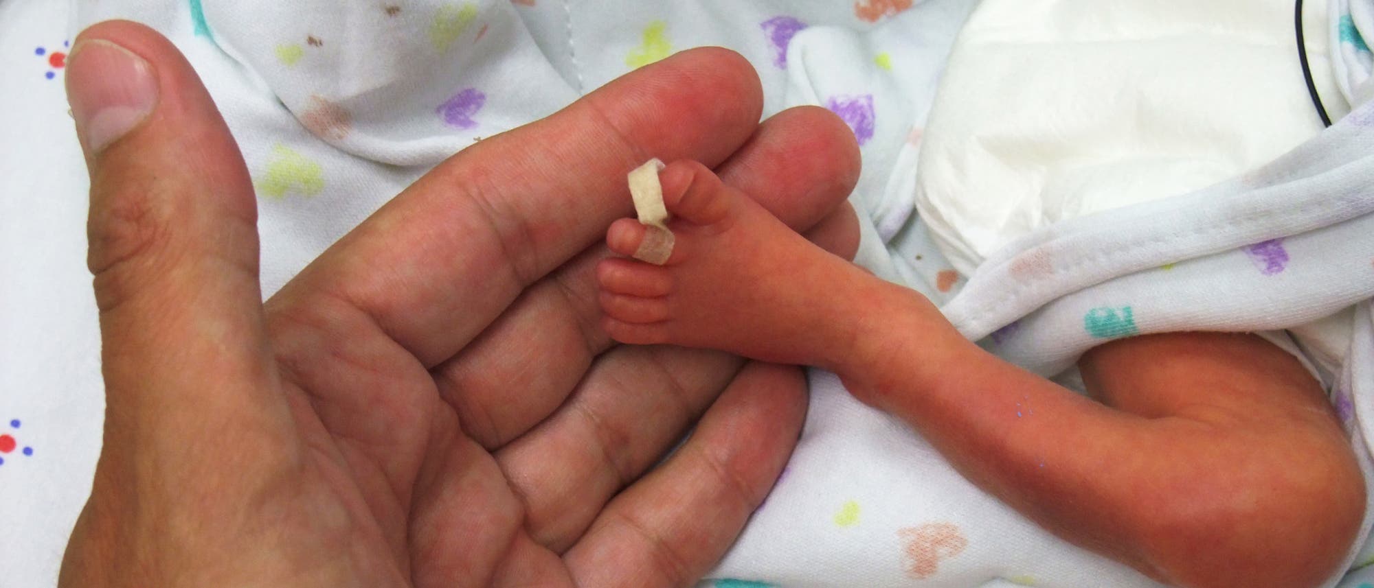 Vater hält Fuß seines frühgeborenen Babys Vater hält Fuß seines frühgeborenen Babys