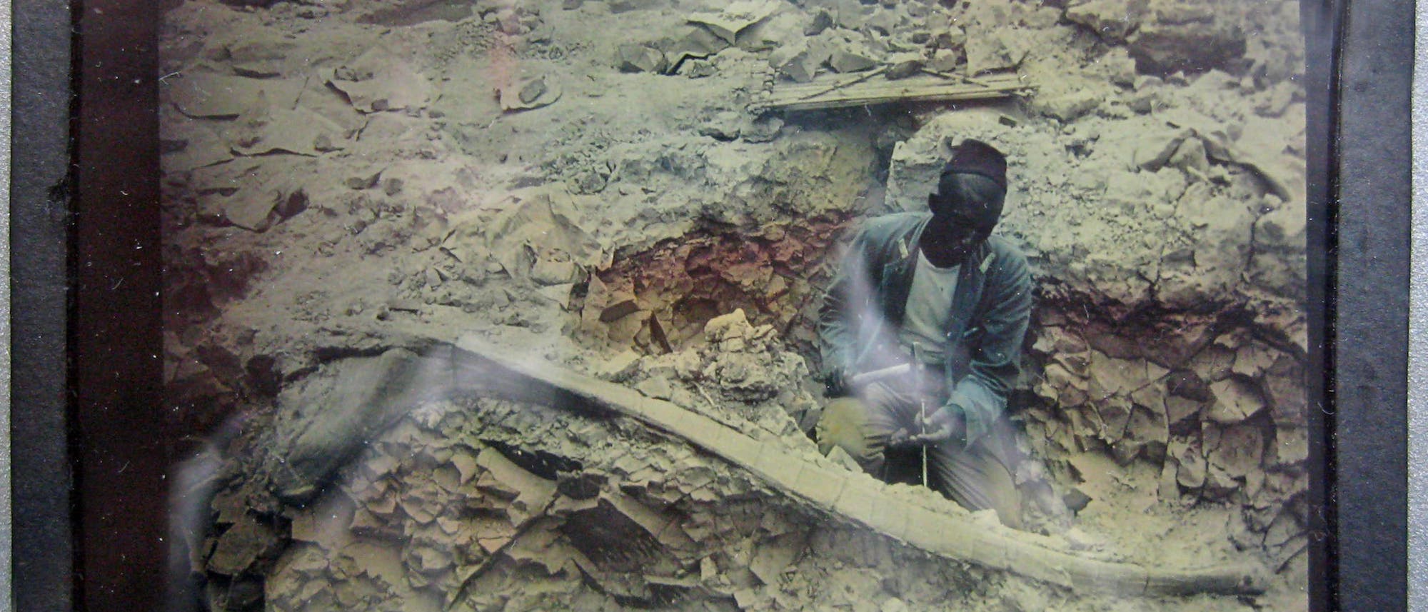 Fossiliengrabung am Tendaguru zwischen 1909 und 1913. Der Text auf dem Diapositiv lautet: »Oberaufseher präpariert große Rippe.«