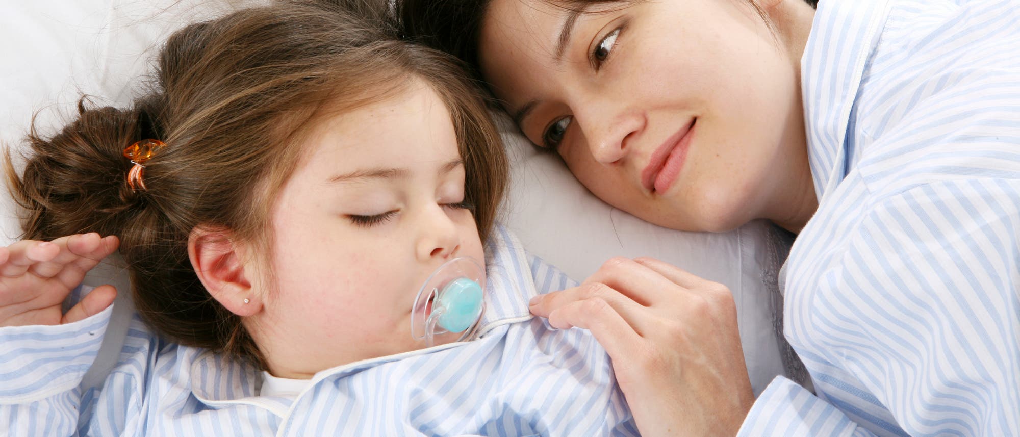 Kleinkind schläft neben seiner Mutter Kleinkind schläft neben seiner Mutter