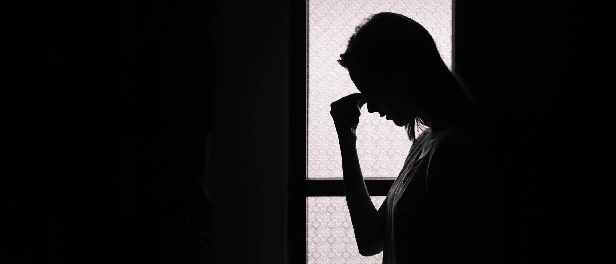 Frau hat sich in dunkles Zimmer zurückgezogen Frau hat sich in dunkles Zimmer zurückgezogen