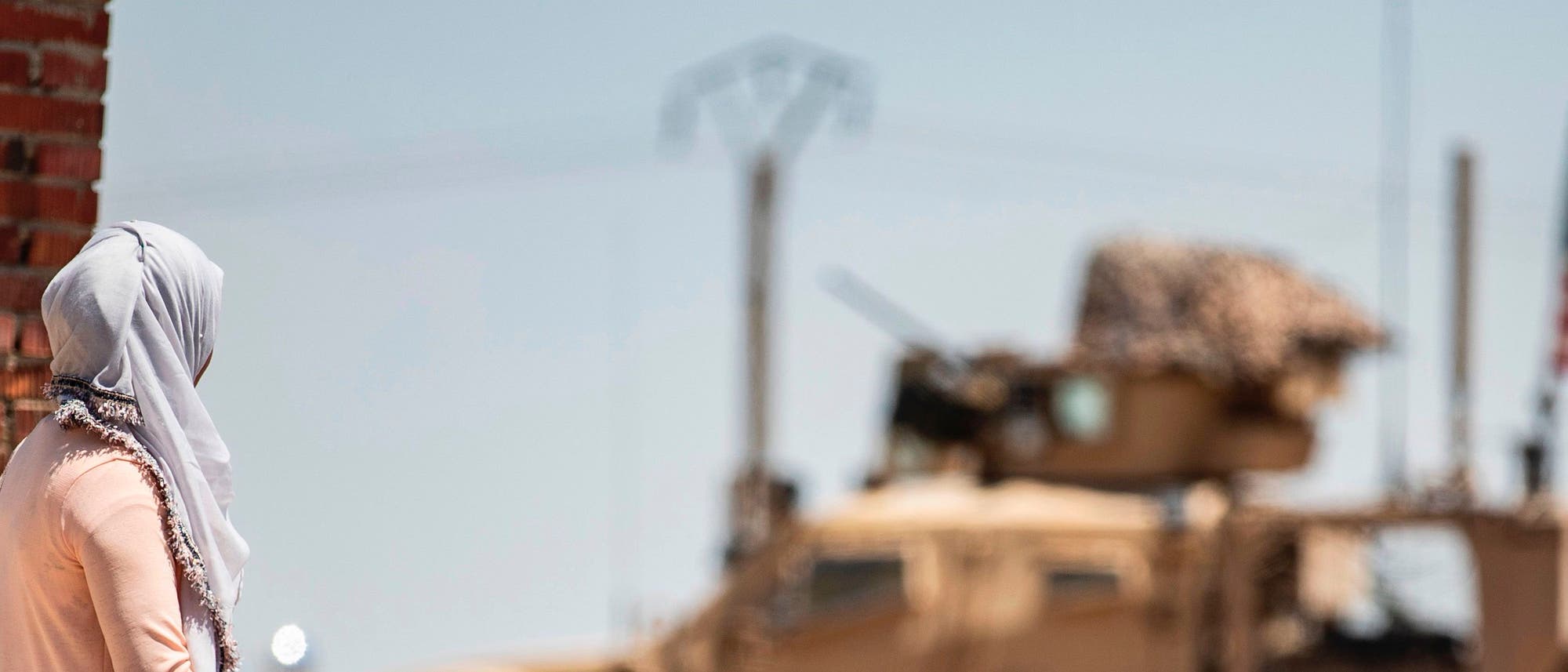 Menschen in Syrien beobachten ein US-Militärfahrzeug. Menschen in Syrien beobachten ein US-Militärfahrzeug.