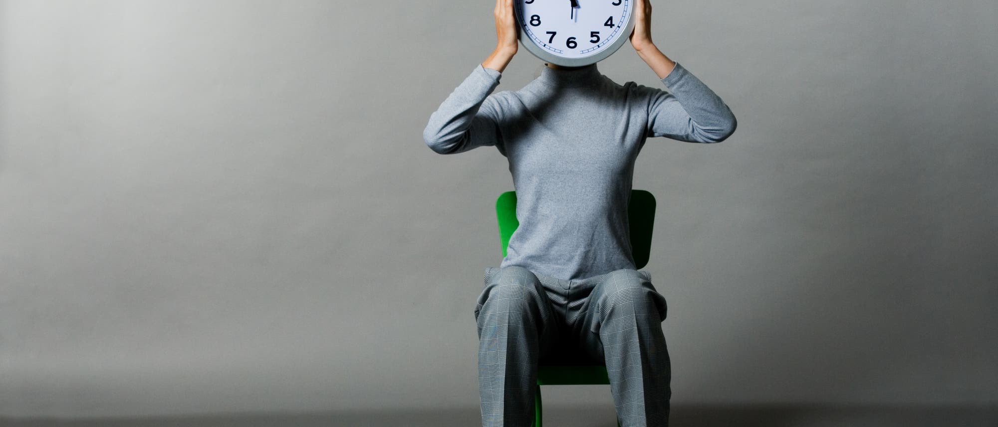 Auf einem Stuhl sitzt ein menschlicher Körper mit Uhr als Kopf. Auf einem Stuhl sitzt ein menschlicher Körper mit Uhr als Kopf.
