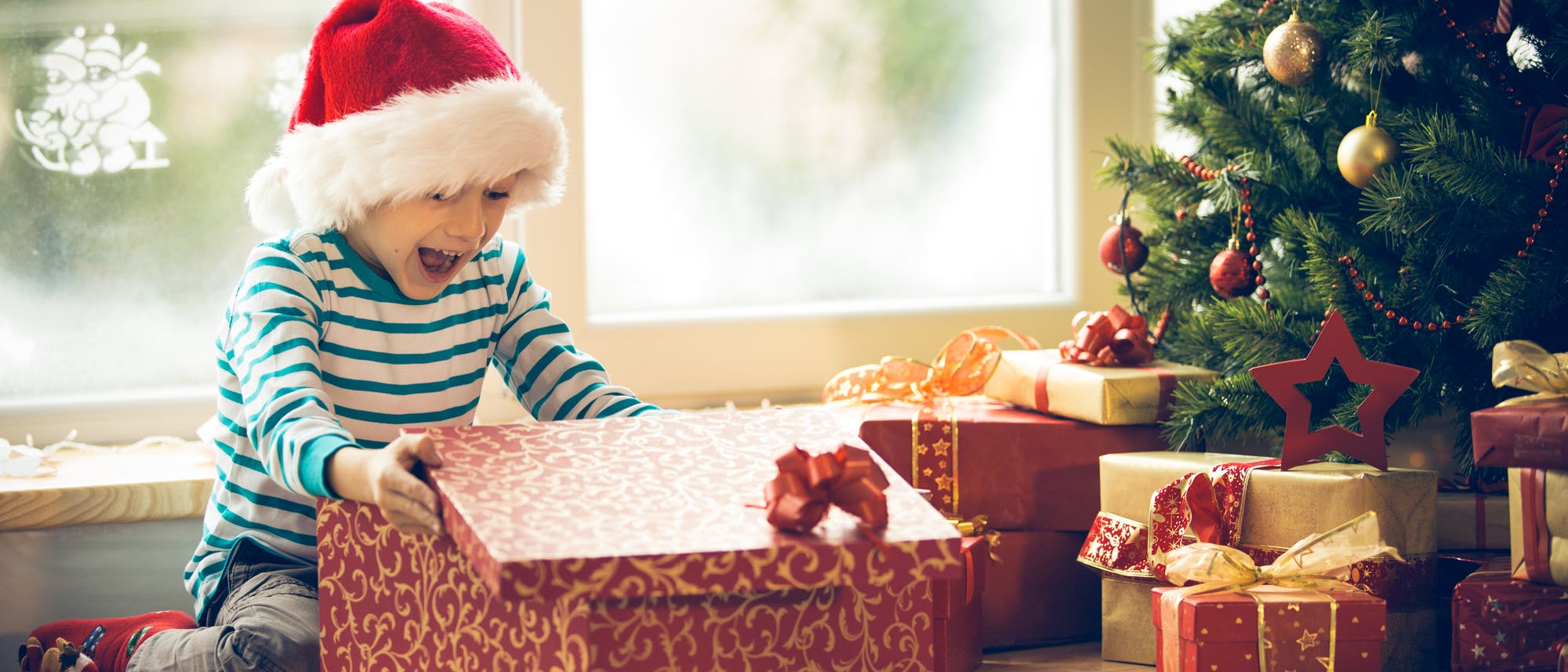 Eine fröhlicher Junge packt sein Geschenk aus Eine fröhlicher Junge packt sein Geschenk aus
