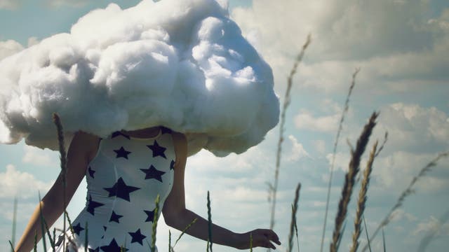 Eine Frau mit Wolkenkopf läuft durch ein Feld