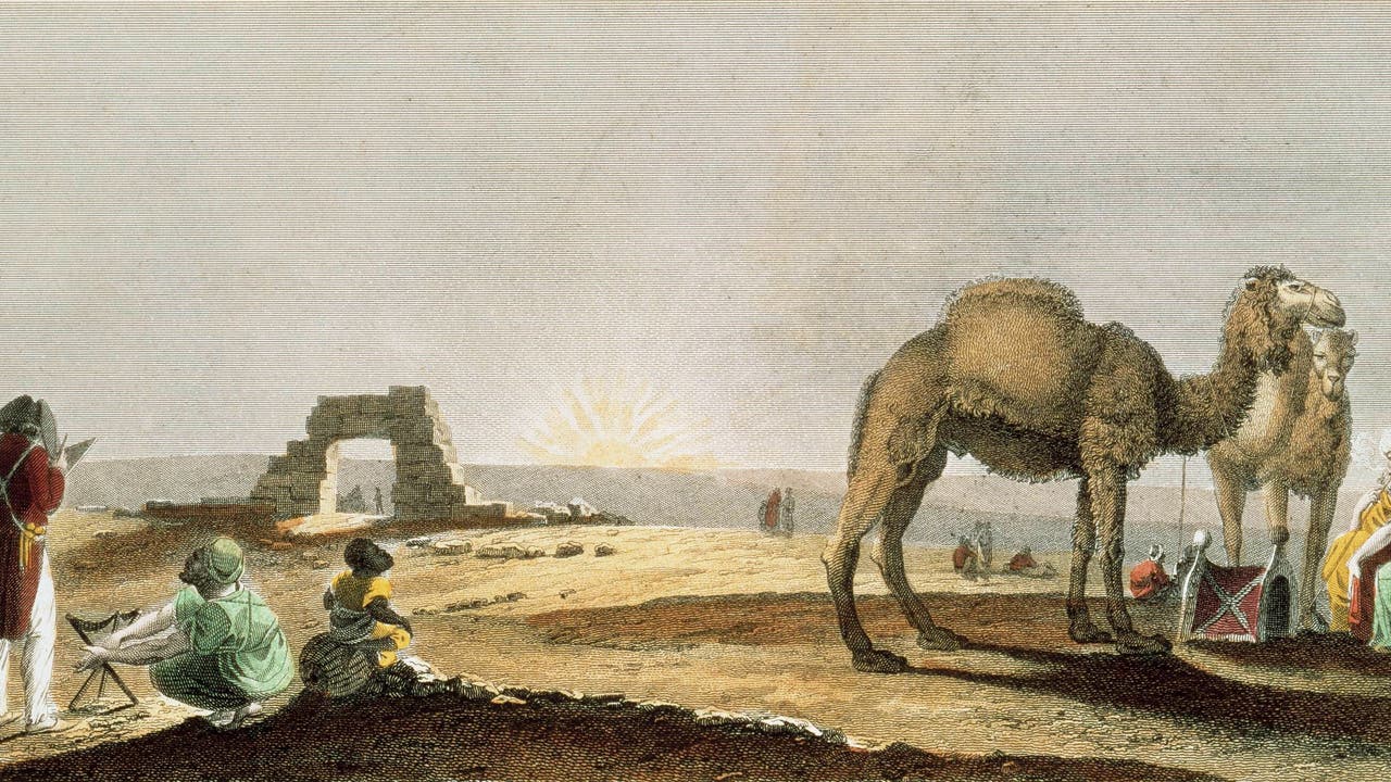 Eine historische Illustration zeigt eine Wüstenlandschaft bei Sonnenaufgang. Im Vordergrund stehen zwei Kamele, neben denen zwei Personen in traditionellen Gewändern sitzen. Links sind weitere Personen zu sehen, darunter eine Person, die auf einer Staffelei malt. Im Hintergrund ist eine Ruine zu erkennen. Die Szene vermittelt eine ruhige, historische Atmosphäre in einer Wüstenumgebung.