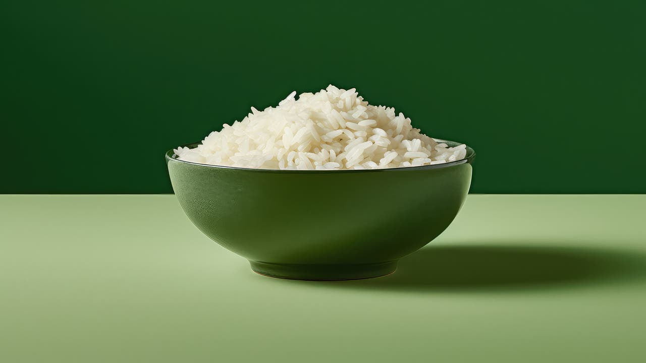 Eine grüne Schale voll weißem Reis vor einem grünen Hintergrund