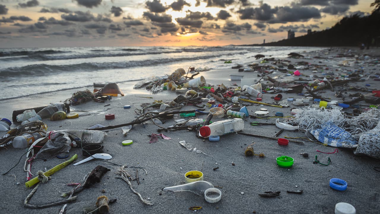 Ein Strand im Abendlicht ist übersät mit Plastikmüll