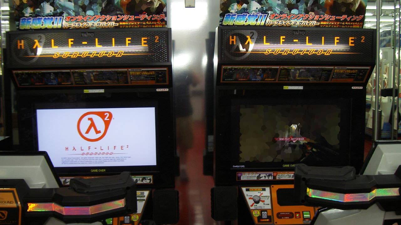 Zwei Arcade-Spielautomaten mit dem Spiel "Half-Life 2: Survivor". Der linke Bildschirm zeigt das Logo des Spiels mit dem Lambda-Symbol und der Aufschrift "Half-Life 2". Der rechte Bildschirm zeigt eine Spielsituation. Beide Automaten sind mit Steuerungselementen ausgestattet und befinden sich in einer Spielhalle.