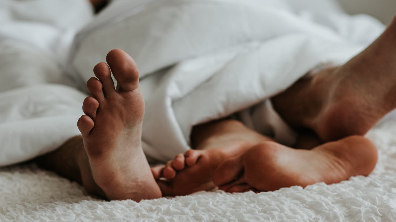 Füße eines Paares unter einer Bettdecke