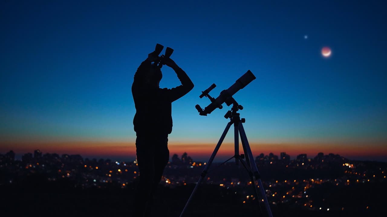Silhouette einer Person mit Fernglas vor dem Hintergrund eines dunklen Himmels.