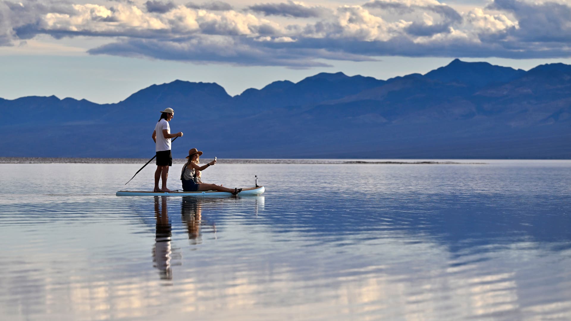 zwei Menschen befinden sich auf einem Standup Paddle und gleiten über den Lake Manly im Death Valley im Abendlicht
