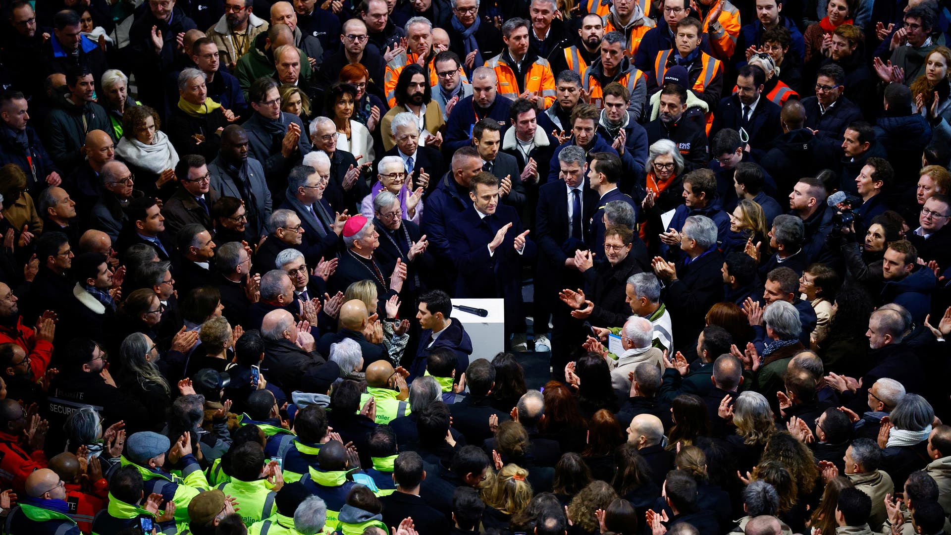 Der französische Staatspräsident Emmanuel Macron inmitten der zahlreichen Handwerkerinnen und Handwerkern, die Notre-Dame restauriert haben.