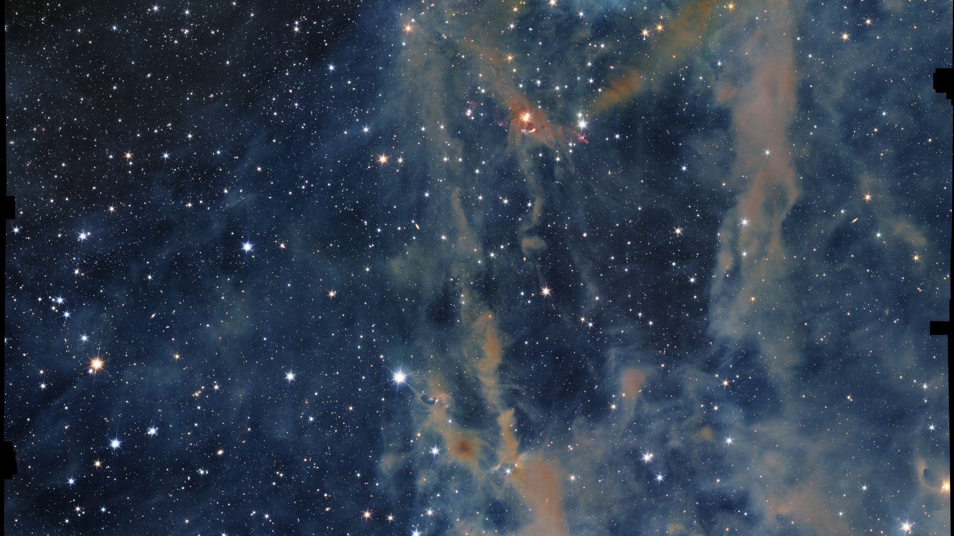 Ein Bild des Weltraums, das einen dichten Sternenhimmel mit zahlreichen leuchtenden Sternen zeigt. Im Vordergrund sind farbige Gas- und Staubwolken zu sehen, die in Blau- und Orangetönen leuchten. Diese Wolken bilden komplexe Strukturen und verleihen dem Bild eine dynamische Tiefe. Der Hintergrund ist dunkel, was die Helligkeit der Sterne und die Details der Nebel betont. Das Bild vermittelt die Weite und Schönheit des Universums.