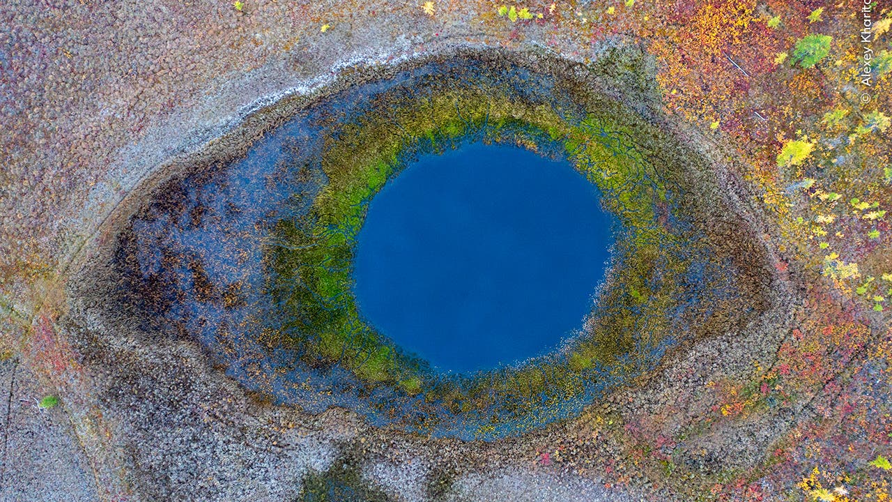 Eine Luftaufnahme eines Sees in der arktischen Tundra. Aus der Luft wirken Wasser und Ufer wie ein Auge.