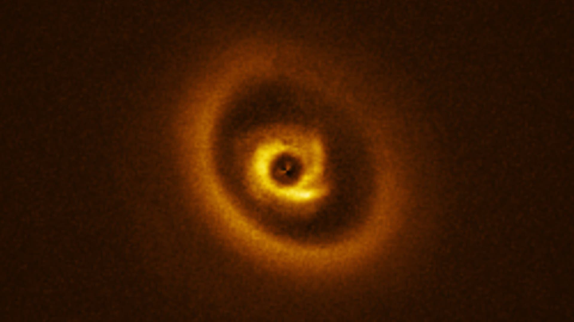 Ein leuchtender, spiralförmiger Protoplanetarer Nebel im Weltraum, der in warmen Gelbtönen auf einem dunklen Hintergrund leuchtet. Die Struktur zeigt mehrere konzentrische Ringe um einen zentralen Punkt. 
