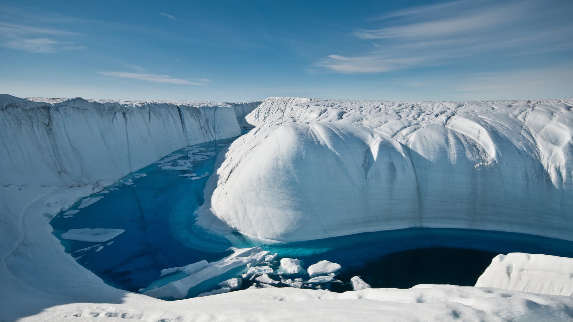Ein Schmelzwasserstrom fräßt sich tief in das Gletschereis ein.